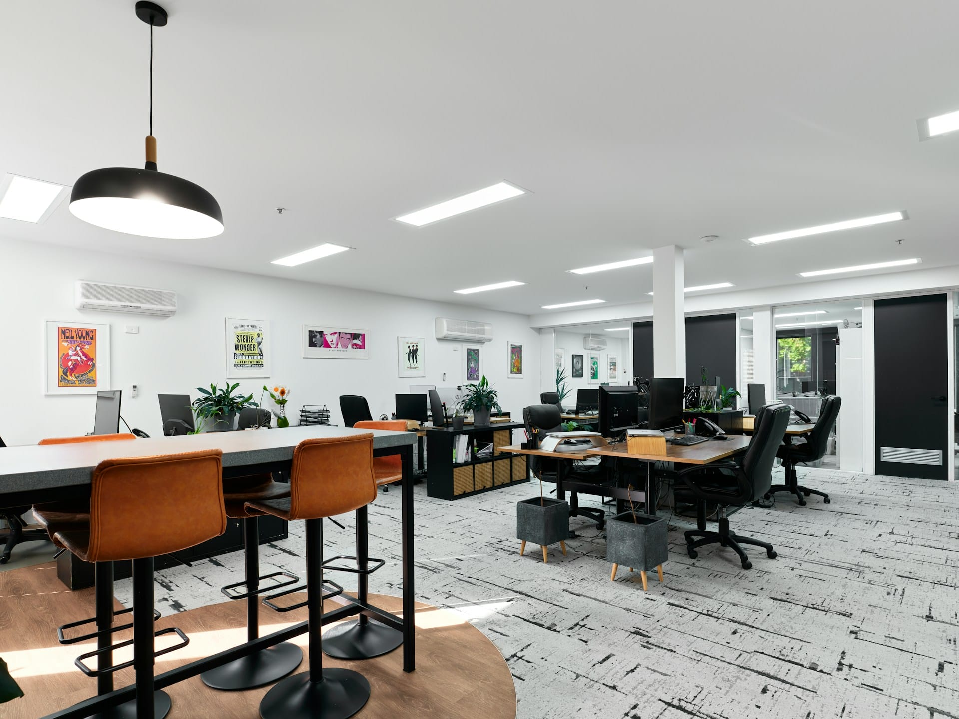 Spotless modern open-plan office space with desks, computers, and break area, showcasing commercial cleaning results.